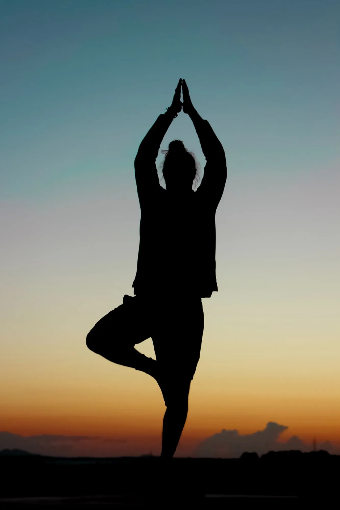 Silhouette of a yoga tree pose at sunset